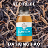 A 250 ml bottle of Craft & Culture Kombucha, set against a backdrop of dried black tea leaves, features the bold slogan "Trust Your Gut. Feel Amazing." The words "Red Robe Da Hong Pao" elegantly highlight its rich black tea origins.