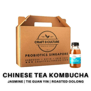 A cardboard carrier with the "Craft & Culture - Kombucha, Kefir & Probiotics Singapore" logo holds a white-capped bottle labeled "Chinese Tea Series - The Classics," highlighting Jasmine, Tie Kuan Yin, and Roasted Oolong for an exquisite kombucha experience.