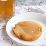 A round, beige kombucha SCOBY sits on a white plate highlighting its gelatinous texture, while in the background, Craft & Culture - Kombucha, Kefir & Probiotics Singapore invites you to explore probiotics benefits through their [New & Updated] Kombucha Masterclass Workshop.